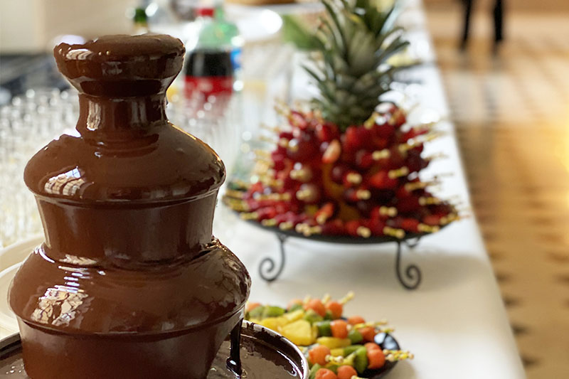 fontaine de chocolat sur une table de buffet avec compositions de brochettes de fruits