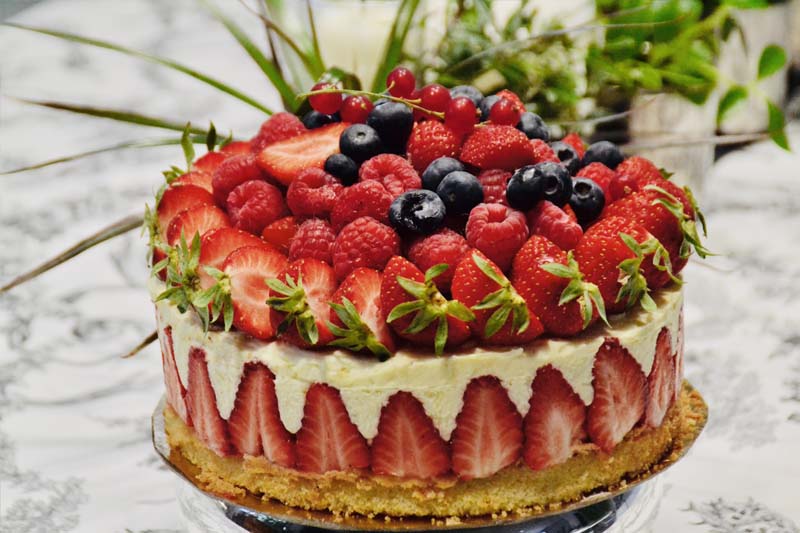 gâteau dressé aux fraises et framboises sur une table nappée