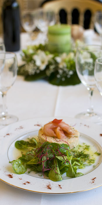 assiette dressée de saumon et salade avec centre de table en arrière plan