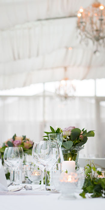table dressée avec verres, couverts, bougies, bouquets de fleurs